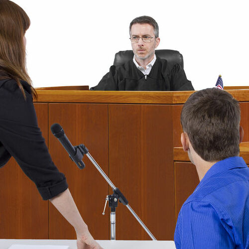 defendant with lawyer speaking to a judge in the courtroom
