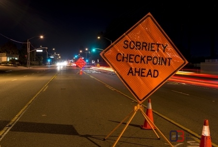 Orange road sign that reads sobriety checkpoint ahead