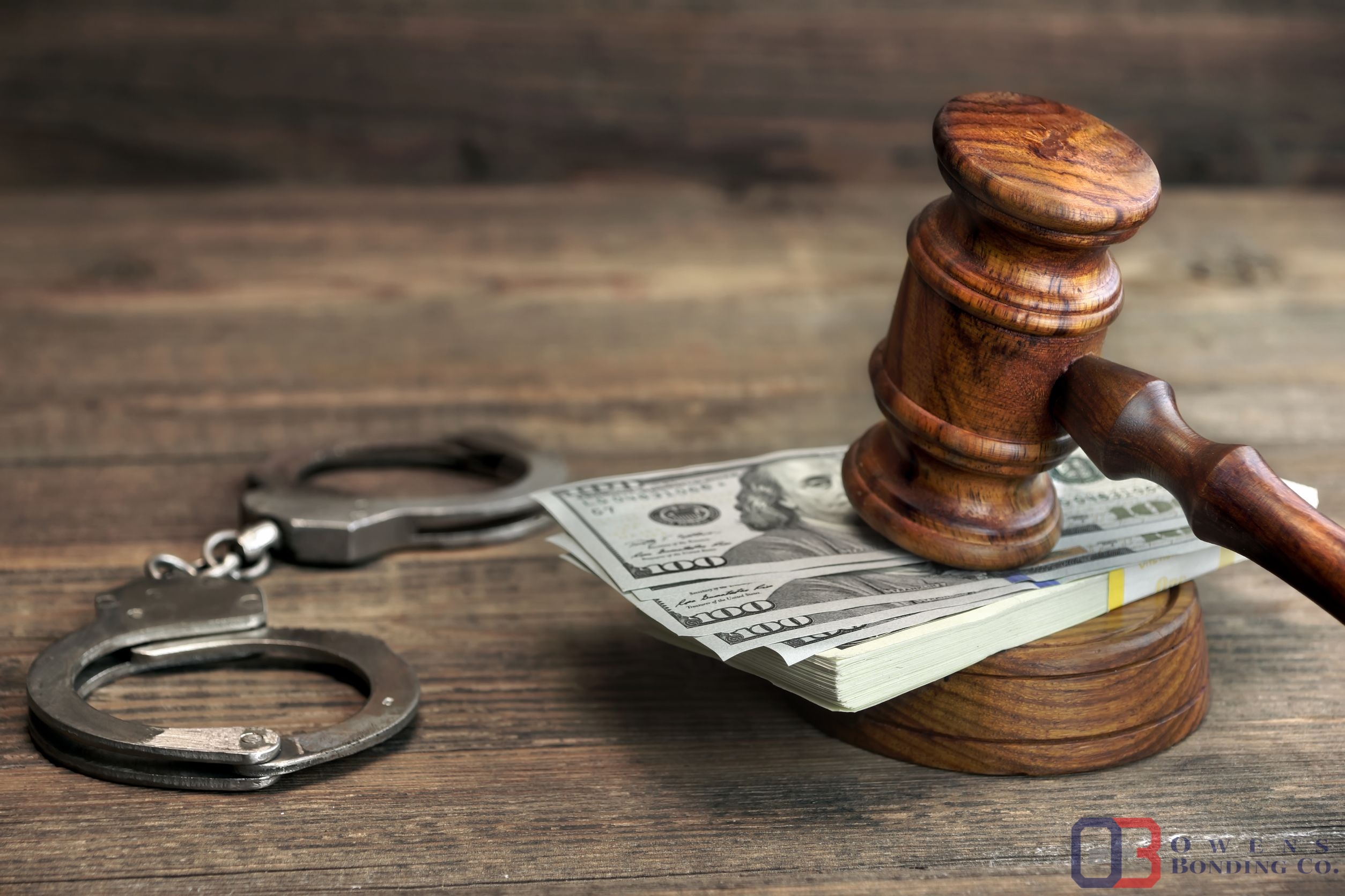 usa dollar money cash, real handcuffs and judge gavel on rough wood background. concept for arrest, corruption, bail, crime, bribing or fraud.